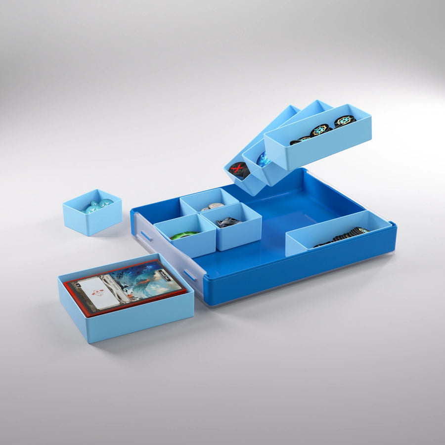 A photo of a blue, plastic container on a white background. The plastic container has smaller containers, some inside the larger frame, some sitting to the side, and some floating above. All of the smaller containers are filled with board game pieces and cards.